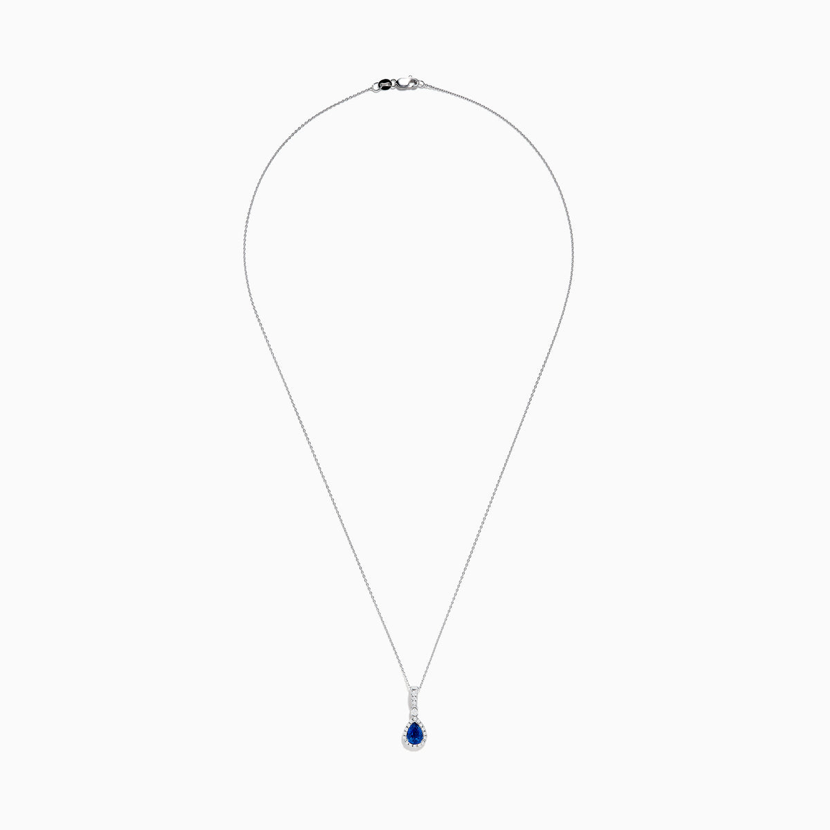 The 14K White Gold Pear Shape Blue Sapphire and Diamond Pendant features a teardrop blue sapphire framed by small clear stones and accented with diamonds set above the main gem.