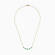 The 14K Yellow Gold Emerald and Diamond Necklace showcases alternating round emerald and diamond stones set in a gentle curve at the center.
