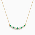 The 14K Yellow Gold Emerald and Diamond Necklace showcases alternating round emerald and diamond stones set in a gentle curve at the center.