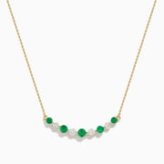 The 14K Yellow Gold Emerald and Diamond Necklace showcases alternating round emerald and diamond stones set in a gentle curve at the center.