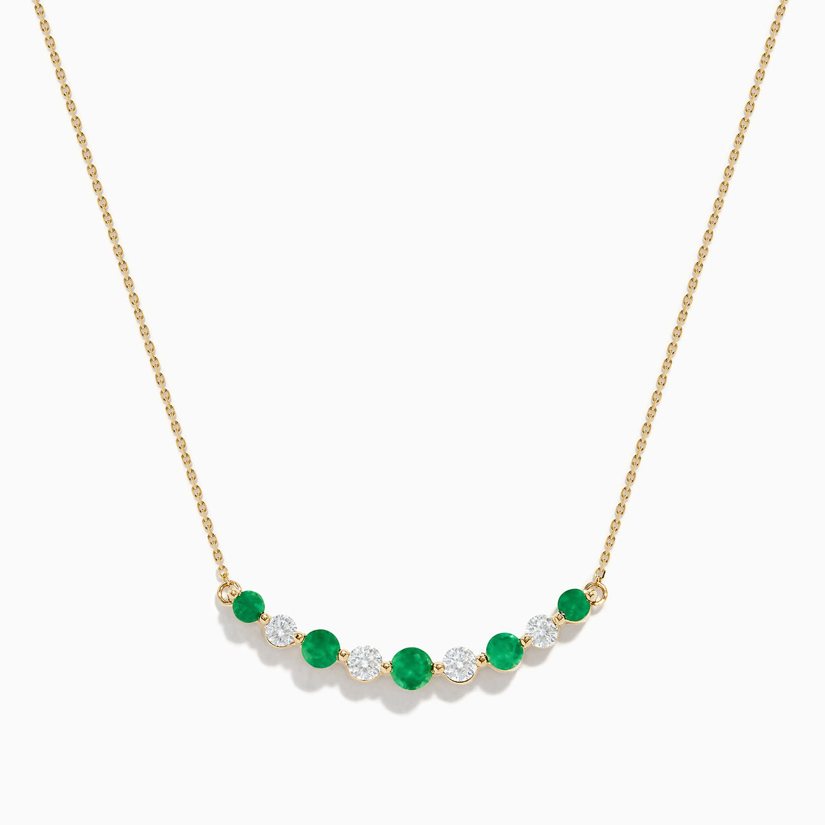 The 14K Yellow Gold Emerald and Diamond Necklace showcases alternating round emerald and diamond stones set in a gentle curve at the center.