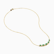 The 14K Yellow Gold Emerald and Diamond Necklace showcases alternating round emerald and diamond stones set in a gentle curve at the center.