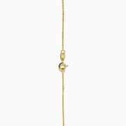 The 14K Yellow Gold Emerald and Diamond Necklace showcases alternating round emerald and diamond stones set in a gentle curve at the center.