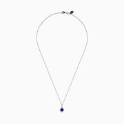 The 14K White Gold Tanzanite and Diamond Halo Pendant showcases a round tanzanite encircled by sparkling diamonds, set on a delicate chain, against a white background.