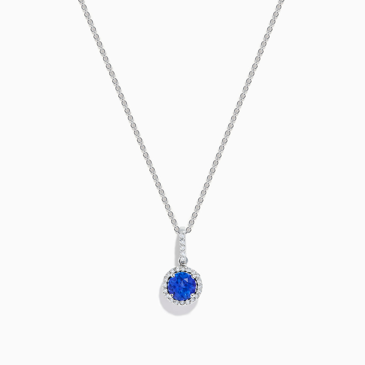 The 14K White Gold Tanzanite and Diamond Halo Pendant showcases a round tanzanite encircled by sparkling diamonds, set on a delicate chain, against a white background.