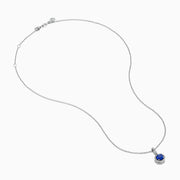 The 14K White Gold Tanzanite and Diamond Halo Pendant showcases a round tanzanite encircled by sparkling diamonds, set on a delicate chain, against a white background.