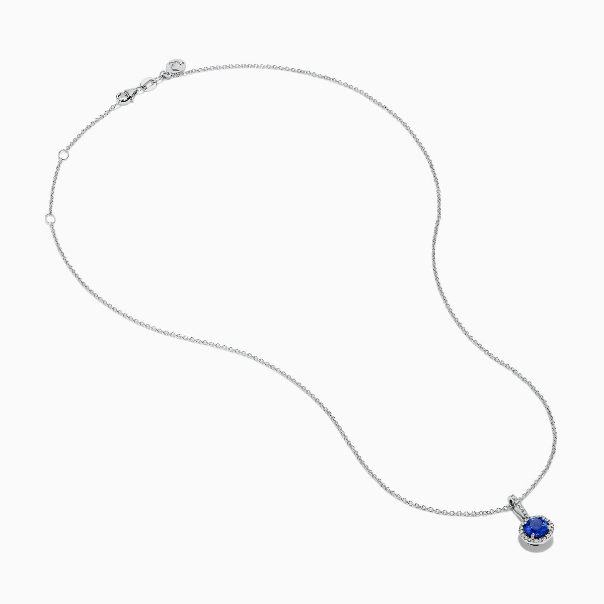 The 14K White Gold Tanzanite and Diamond Halo Pendant showcases a round tanzanite encircled by sparkling diamonds, set on a delicate chain, against a white background.