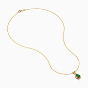 The 14K Yellow Gold Emerald and Diamond Pear Halo Pendant features an emerald teardrop surrounded by a diamond halo, set on a gold chain.