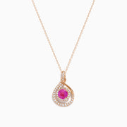 The 14K Rose Gold Pink Sapphire and Diamond Swirl Pendant features a teardrop swirl design with a central pink sapphire encircled by two rows of sparkling white diamonds.