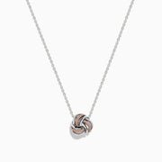 The 14K White Gold Pink Diamond Love Knot Pendant features intertwined rose gold and white gold tones with a polished, textured finish, delicately centered on a silver chain.