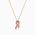 The 14K Rose Gold Pink Sapphire Ribbon Pendant features a pink ribbon-shaped charm encrusted with sparkling pink sapphires on a gold chain, displayed on a white background for a delicate, feminine look.