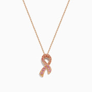 The 14K Rose Gold Pink Sapphire Ribbon Pendant features a pink ribbon-shaped charm encrusted with sparkling pink sapphires on a gold chain, displayed on a white background for a delicate, feminine look.