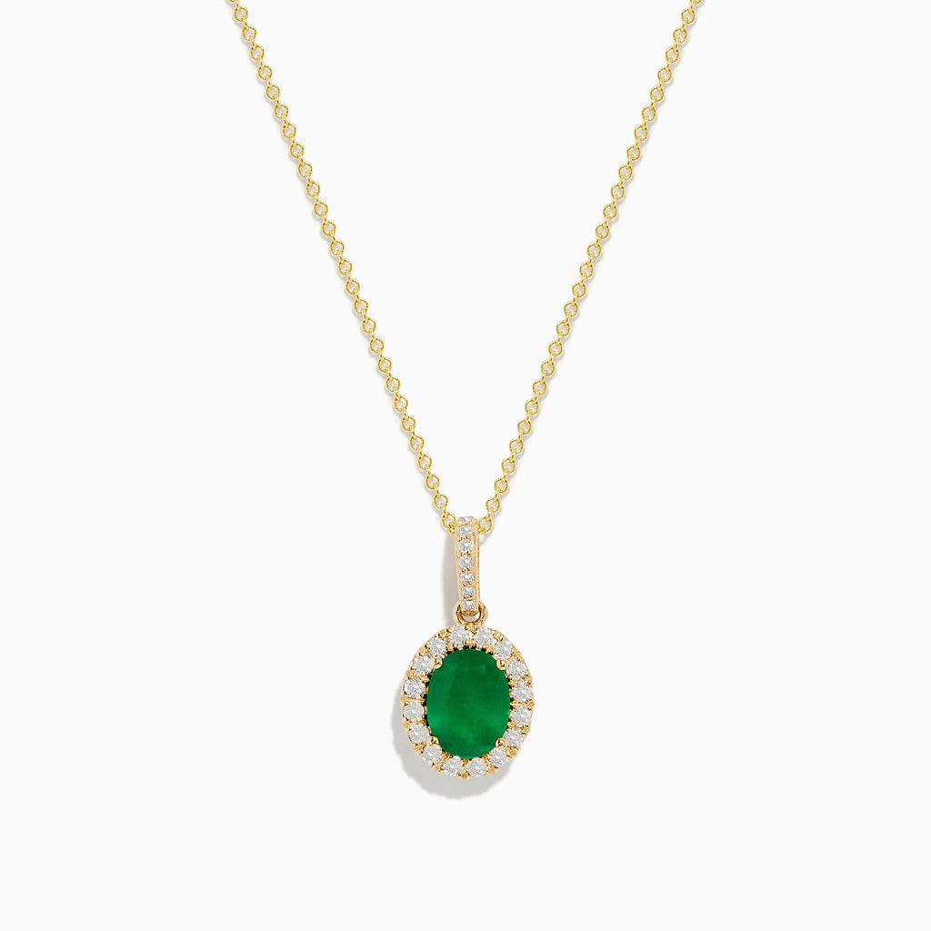 The 14K Yellow Gold Emerald and Diamond Pendant features an oval emerald surrounded by diamonds, suspended from a delicate gold chain and displayed against a white background.
