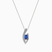 Elegant 14K white gold pendant featuring a curved design and centered with a round blue tanzanite, accented by diamonds, shown on a white background.