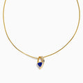 The Nahla Siri 14K Yellow Gold Tanzanite and Diamond Necklace features a delicate chain and a blue tanzanite gemstone pendant, accented with sparkling diamonds, displayed on a white background.