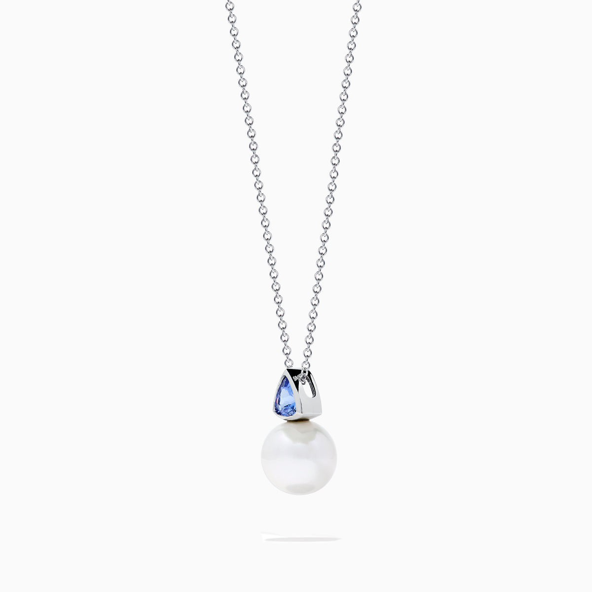 The Nahla 14K White Gold Fresh Water Pearl and Tanzanite Pendant features a round pearl accented with a small, triangular blue tanzanite, all set in white gold and shown against a plain white background.