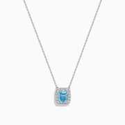 The Lab Grown Blue and White Diamond Halo Necklace in 14K White Gold features a square blue and white diamond pendant surrounded by clear stones, elegantly displayed against a white background.