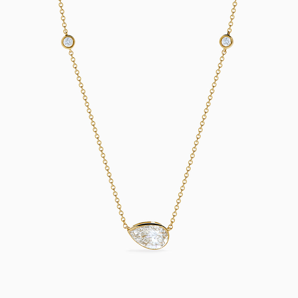 The Lab Grown Diamond Pear Station Necklace in 14K Yellow Gold features a large pear-shaped lab diamond pendant and two small round lab diamonds set along a delicate gold chain.