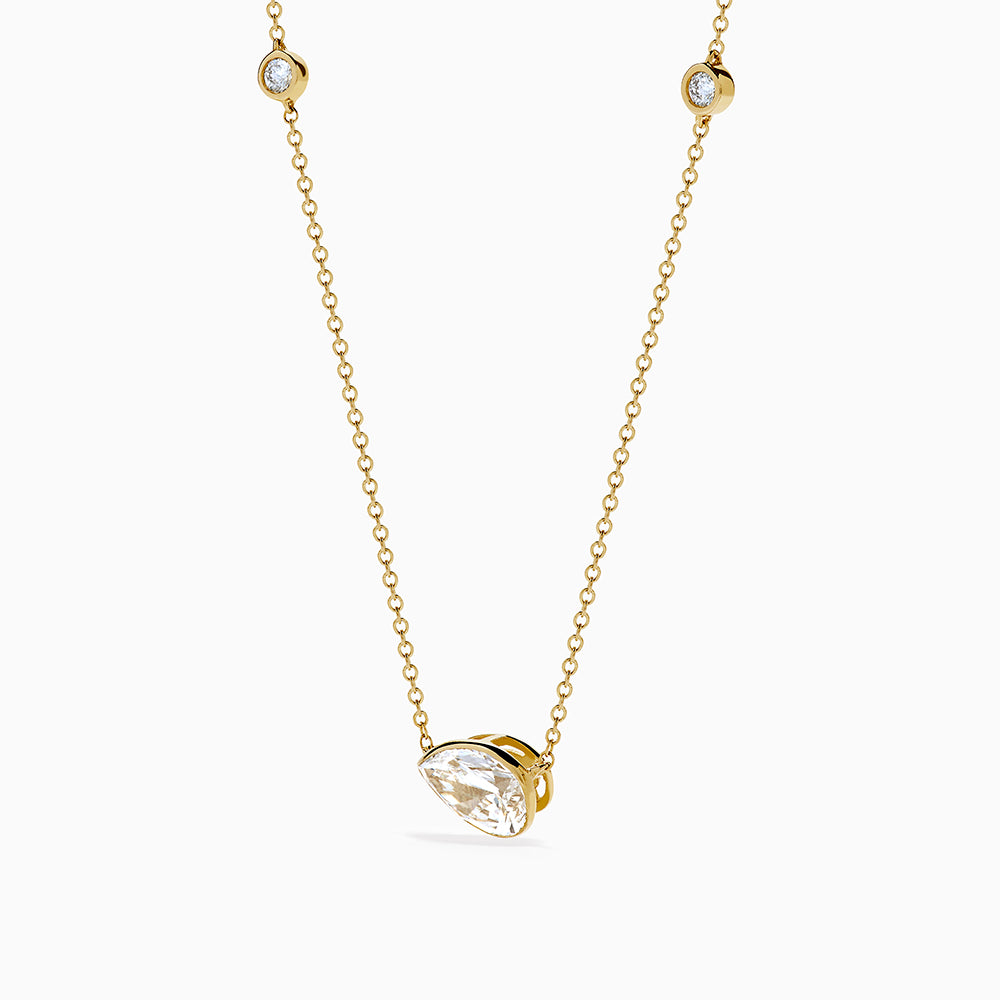 The Lab Grown Diamond Pear Station Necklace in 14K Yellow Gold features a large pear-shaped lab diamond pendant and two small round lab diamonds set along a delicate gold chain.