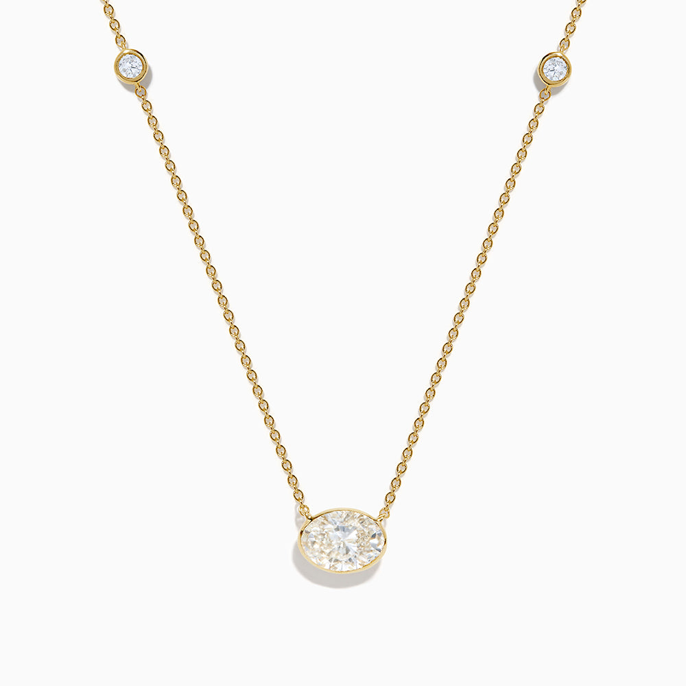 The Lab Grown Diamond Oval Station Necklace in 14K Yellow Gold features a central oval-shaped diamond pendant and two small round diamonds set along each side of the chain, creating an elegant, delicate look.