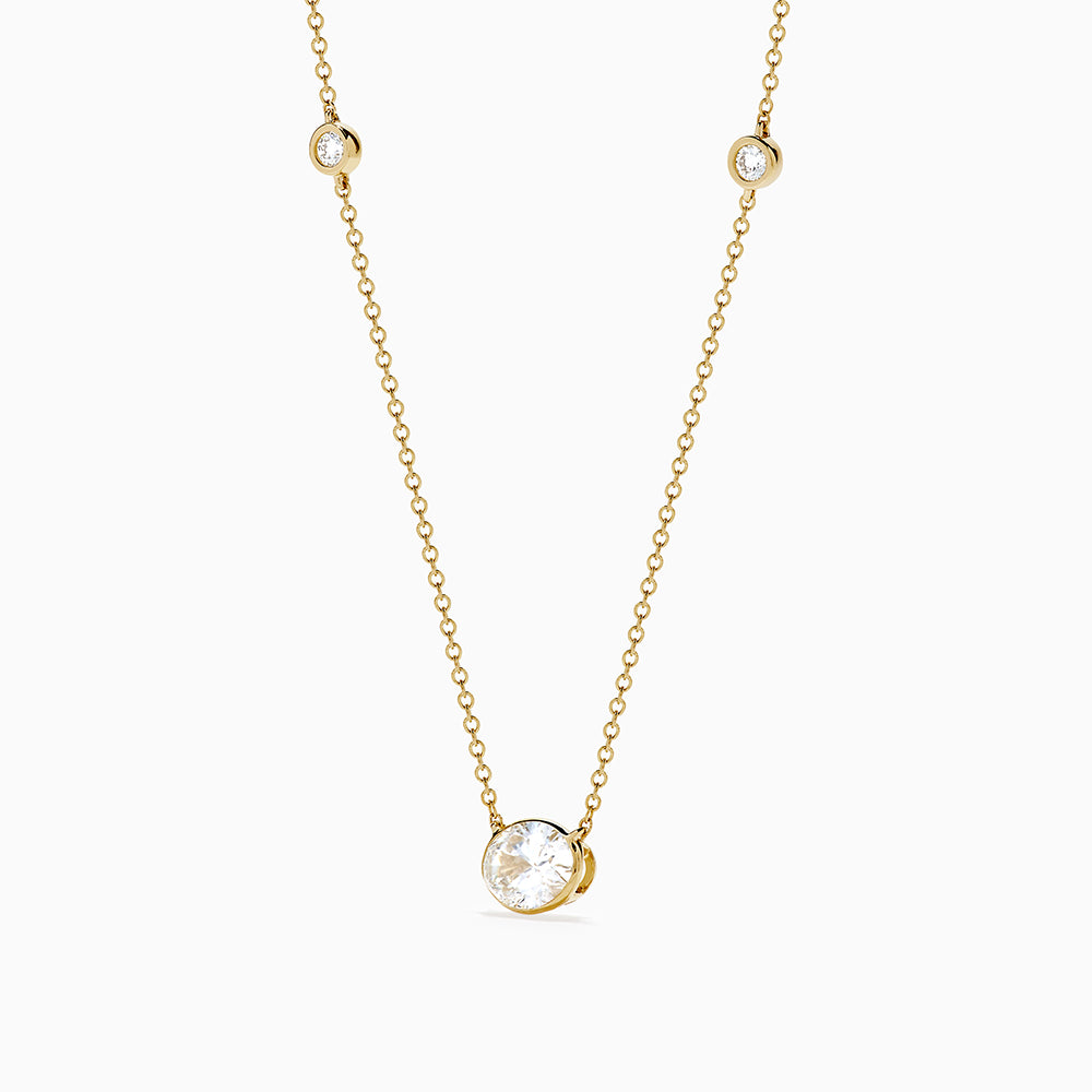 The Lab Grown Diamond Oval Station Necklace in 14K Yellow Gold features a central oval-shaped diamond pendant and two small round diamonds set along each side of the chain, creating an elegant, delicate look.