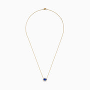 The Nahla 14K White Gold Tanzanite and Diamond Halo Necklace features a central blue oval tanzanite gemstone encircled by diamonds, shown on a white background.