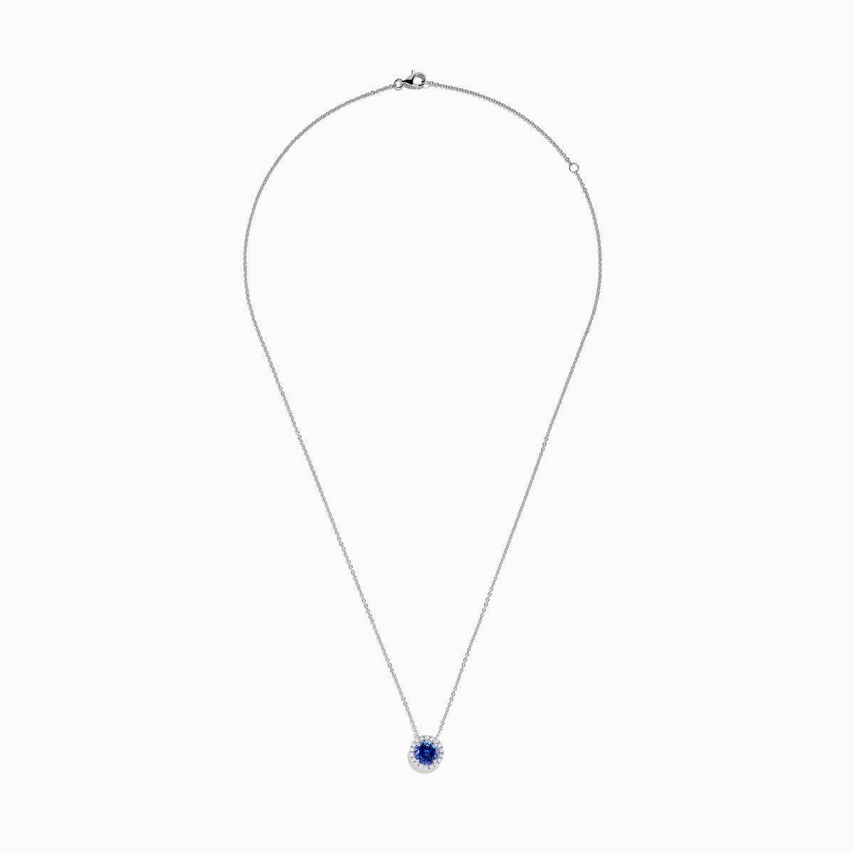The Nahla 14K White Gold Tanzanite and Diamond Halo Necklace features a round blue tanzanite pendant encircled by sparkling diamonds on a delicate silver chain, creating an elegant look against a plain white background.
