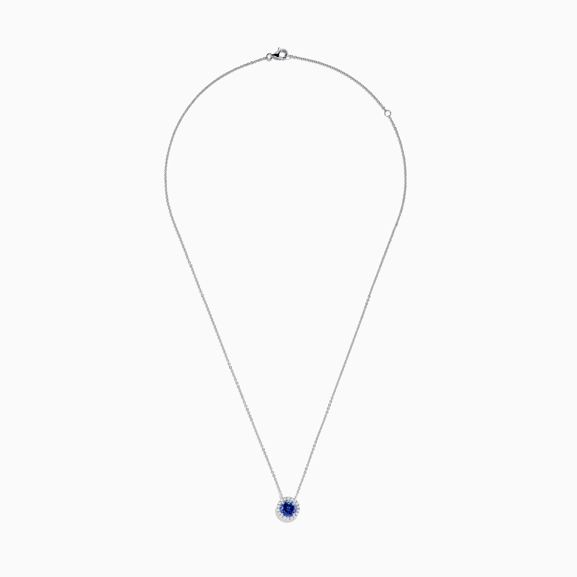 The Nahla 14K White Gold Tanzanite and Diamond Halo Necklace features a round blue tanzanite pendant encircled by sparkling diamonds on a delicate silver chain, creating an elegant look against a plain white background.