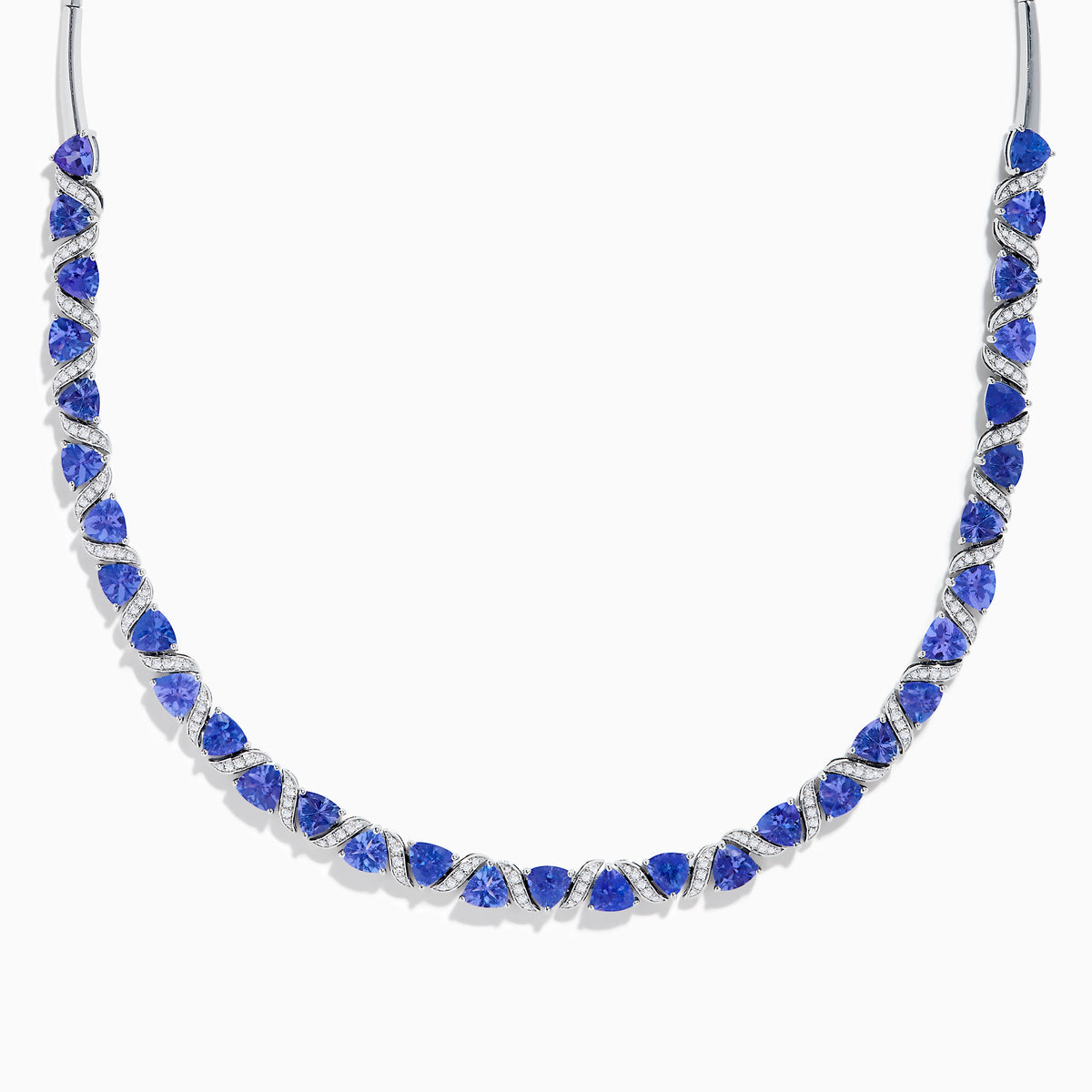 The Nahla Siri 14K White Gold Trillion Cut Tanzanite and Diamond Necklace features alternating deep blue tanzanites and small diamonds set along a 14K white gold chain, elegantly displayed against a white background.