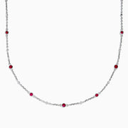 The Ruby Royale 925 Sterling Silver Necklace showcases alternating bezel-set rubies and diamonds along a delicate chain, elegantly displayed against a plain white background.