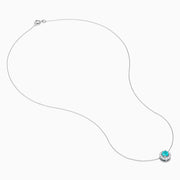 The 18K White Gold Paraiba and Diamond Pendant features a round Paraiba gemstone framed by a halo of white diamonds, elegantly suspended from a fine chain on a white background.
