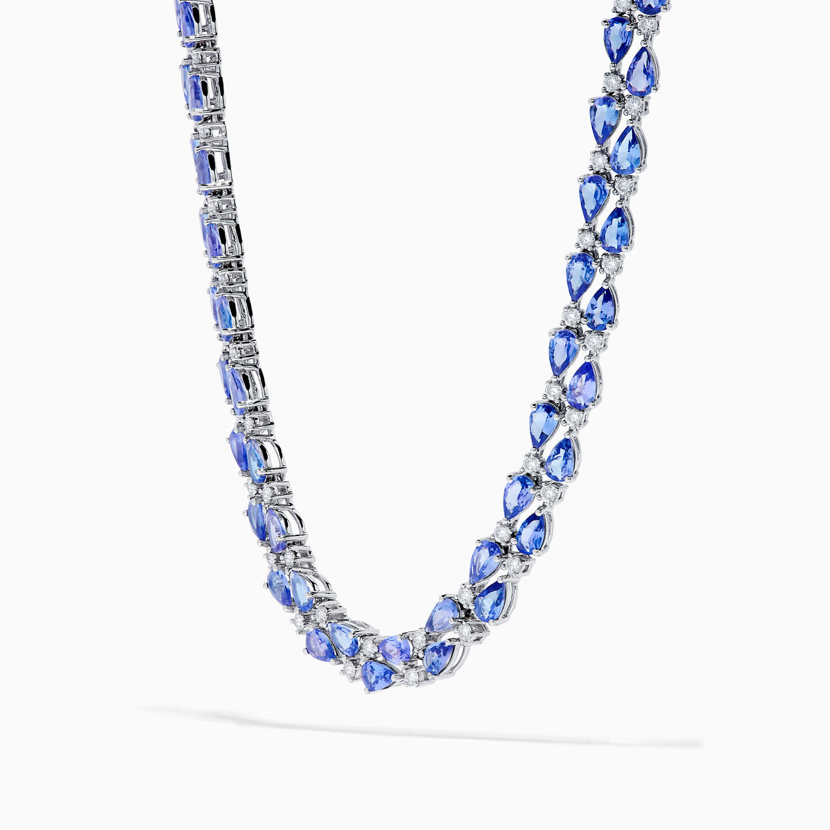 A close-up of the Nahla 14K White Gold Tanzanite and Diamond Necklace, showcasing pear-shaped blue tanzanites and sparkling diamonds set in a symmetrical design against a white background.