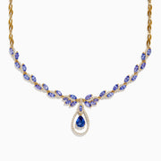 The Nahla Siri 14K Yellow Gold Tanzanite and Diamond Necklace features marquise-cut blue tanzanite gemstones and small diamonds, with a teardrop-shaped tanzanite pendant encircled by a sparkling diamond halo.