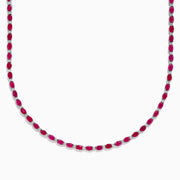 The 925 Sterling Silver Ruby and Diamond Tennis Necklace showcases a continuous row of oval red gemstones in silver prong settings, elegantly displayed against a white background.