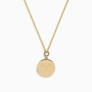 The Zodiac 14K Yellow Gold and Diamond Aries Necklace features a round pendant with an embossed ram, accented by sparkling diamonds, hanging from a delicate gold chain against a white background.