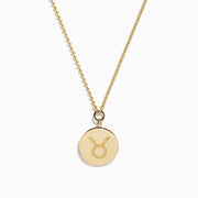 The Zodiac 14K Yellow Gold and Diamond Taurus Necklace features a round pendant with an engraved fish design, accented by diamonds, and hangs from a delicate gold chain on a white background.