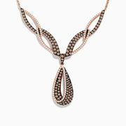 The 14K Rose Gold Espresso and White Diamond Drop Necklace features an intricate design with black and gold sections, encrusted with espresso diamonds, and a striking teardrop-shaped pendant at the center.