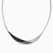 The 14K White Gold Black and White Diamond Necklace features an asymmetrical, sweeping design with textured sections set with small black diamonds.