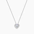 The Lab Grown Heart and Round Diamond Halo Pendant in 14K White Gold features a sparkling heart-shaped lab grown diamond with a halo of smaller diamonds on a delicate silver chain, shown against a plain white background.