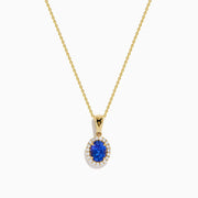 The Nahla 14K Yellow Gold Oval Tanzanite and Diamond Pendant features an oval tanzanite encircled by sparkling diamonds, displayed on a sleek yellow gold chain against a plain white background.