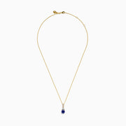 The Nahla 14K Yellow Gold Tanzanite and Diamond Pendant features a round blue tanzanite and white diamonds, set on a yellow gold chain and shown on a white background.