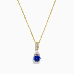 The Nahla 14K Yellow Gold Tanzanite and Diamond Pendant features a round blue tanzanite and white diamonds, set on a yellow gold chain and shown on a white background.
