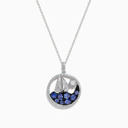 The 925 Sterling Silver Tanzanite and Diamond Sailboat Pendant features a round design with a sailboat, sparkling tanzanite wave accents, and a diamond representing the sun or moon above the boat.