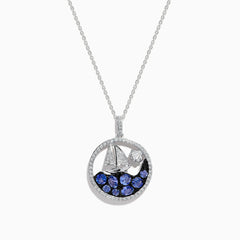 The 925 Sterling Silver Tanzanite and Diamond Sailboat Pendant features a round design with a sailboat, sparkling tanzanite wave accents, and a diamond representing the sun or moon above the boat.