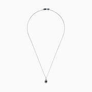 The 14K White Gold Black and White Diamond Halo Pendant showcases an oval black gemstone encircled by sparkling white diamonds, creating a striking contrast against a white background.