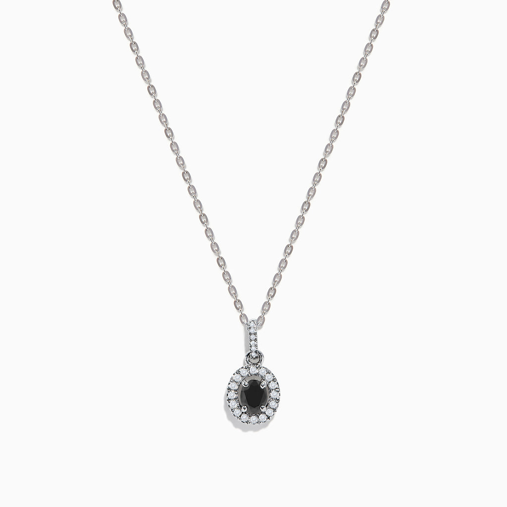 The 14K White Gold Black and White Diamond Halo Pendant showcases an oval black gemstone encircled by sparkling white diamonds, creating a striking contrast against a white background.