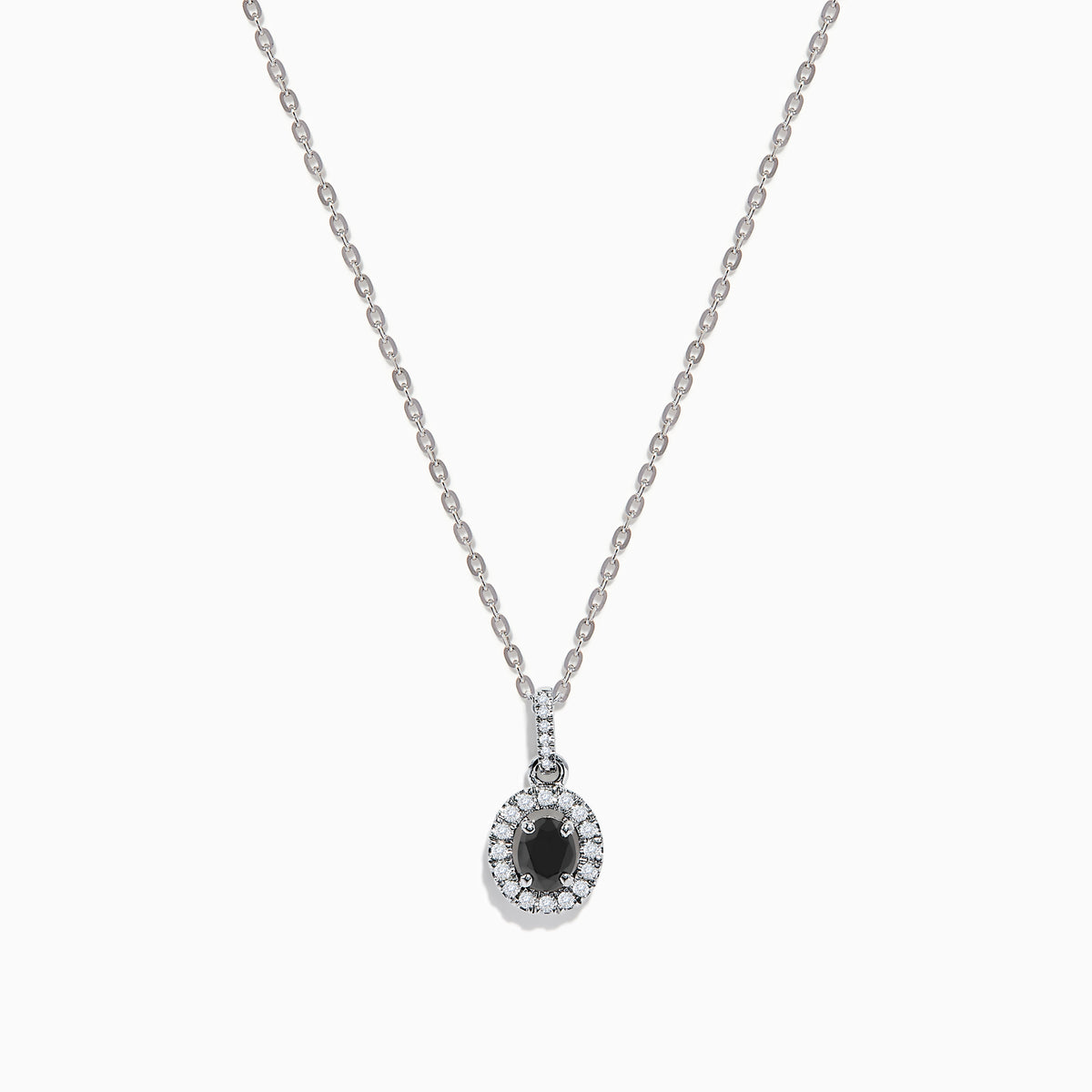 The 14K White Gold Black and White Diamond Halo Pendant showcases an oval black gemstone encircled by sparkling white diamonds, creating a striking contrast against a white background.