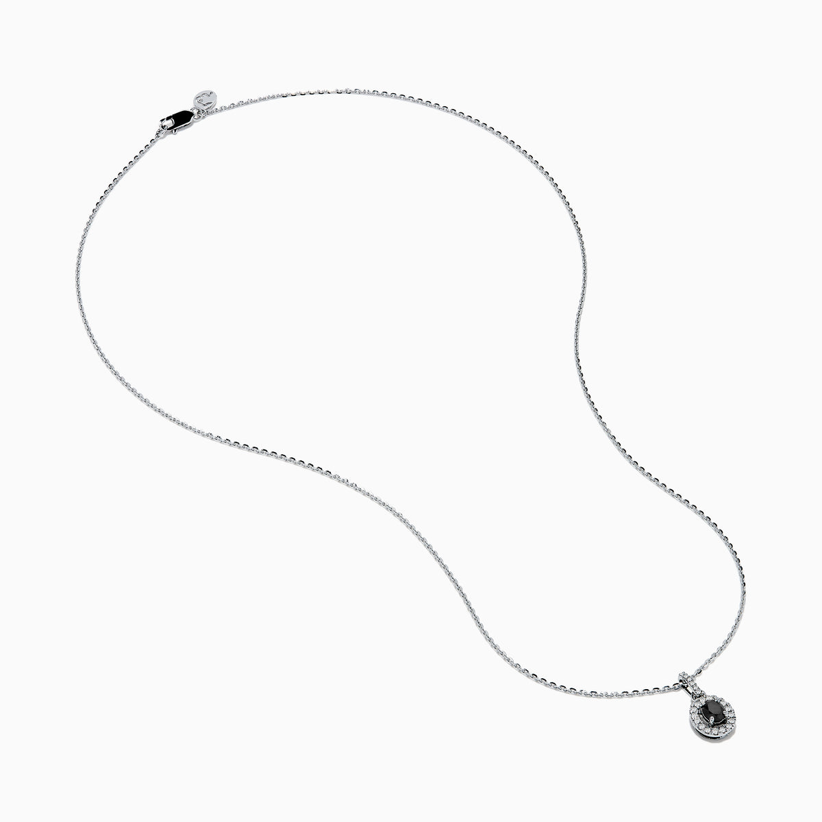 The 14K White Gold Black and White Diamond Halo Pendant showcases an oval black gemstone encircled by sparkling white diamonds, creating a striking contrast against a white background.