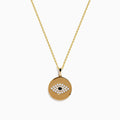 The Novelty 14K Yellow Gold Diamond Evil Eye Disk Pendant features a round design with white and black stones forming the eye, delicately hanging from a gold chain.