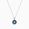 The Bella Bleu 14K White Gold Blue and White Diamond Flower Pendant features a circular floral design with a center cluster of white stones surrounded by sparkling blue and white diamonds.